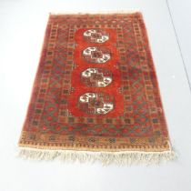 A red-ground Afghan rug. 173x115cm. Some fading and discolouration. Some loss to fringe. Would