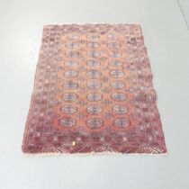 A red-ground Afghan rug. 132x96cm. Very faded. Would benefit from a clean.