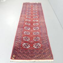 A red-ground Afghan runner. 260x82cm.