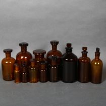 A collection of Mid-century Amber apothecary bottles, various sizes, all including stoppers, largest
