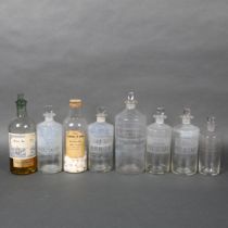 A selection of antique glass apothecary bottles, some with contents and associated labels, largest