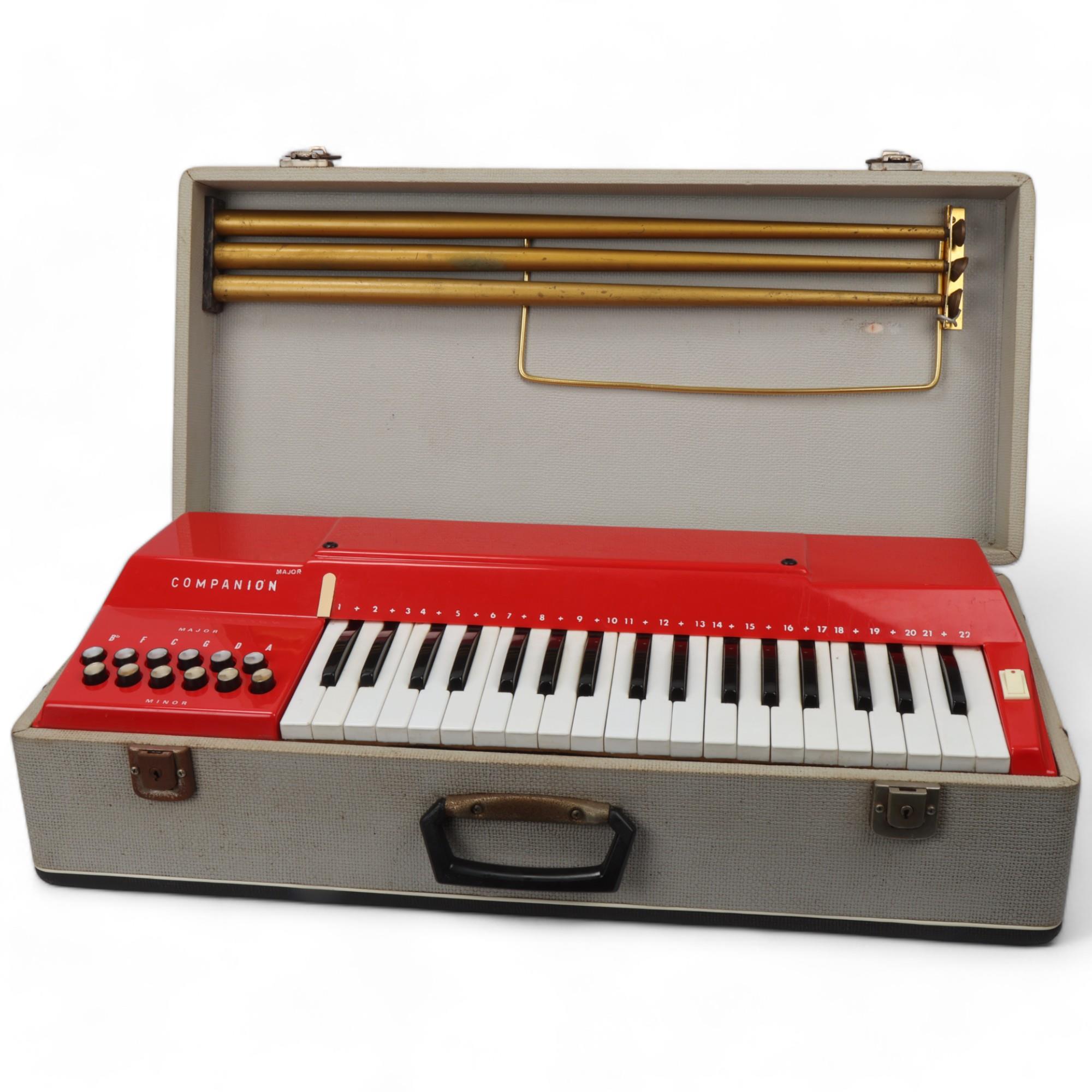 A mid 20th century Italian Companion electric keyboard, red plastic in original fixed carry case and