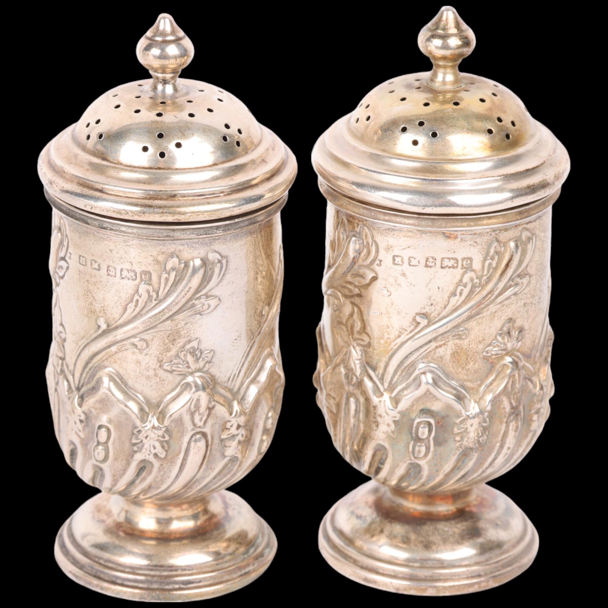 A pair of Art Nouveau Edwardian silver pedestal pepperettes, Henry Matthews, Birmingham 1904, relief