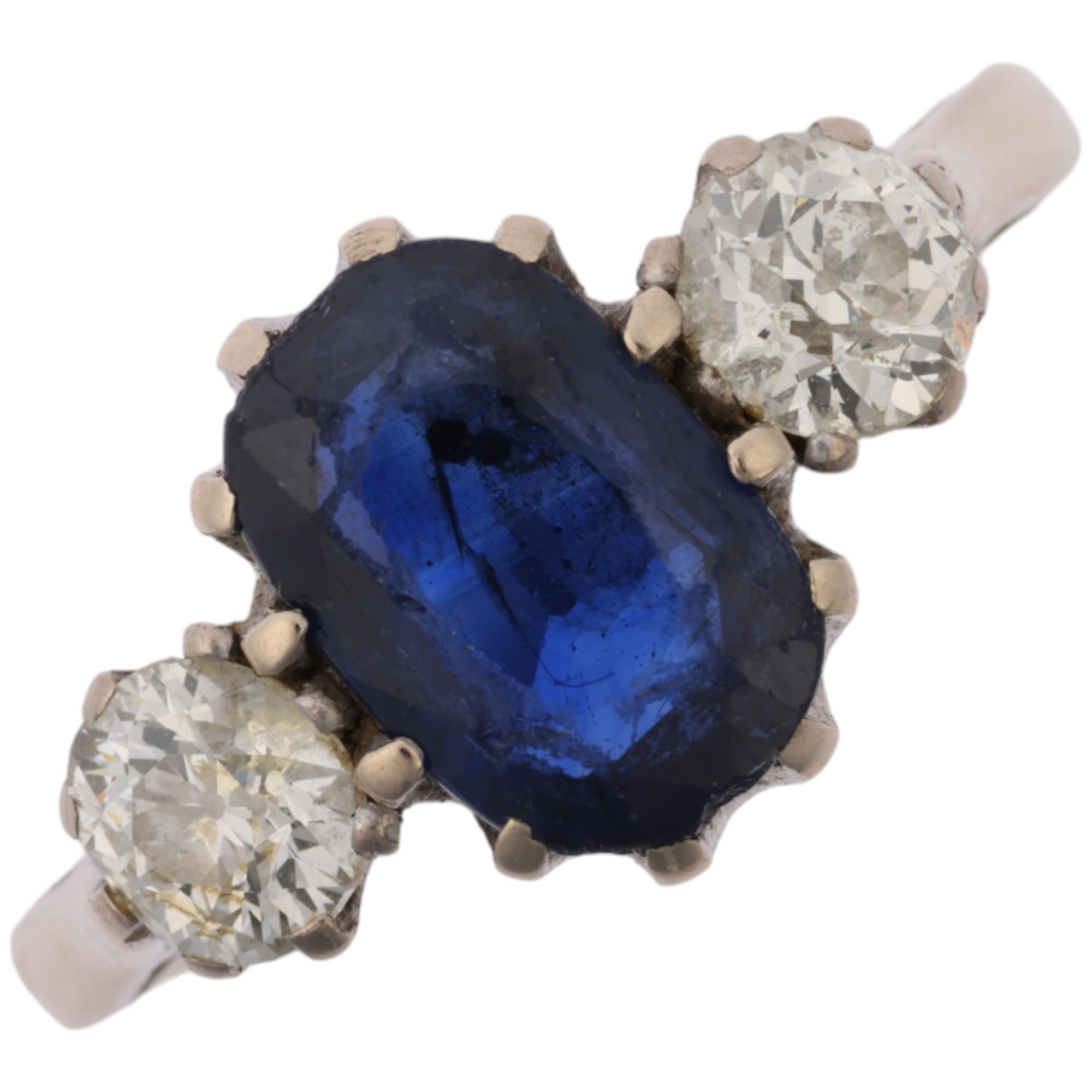 An 18ct white gold three stone sapphire and diamond ring, claw set with 1.7ct oval mixed-cut