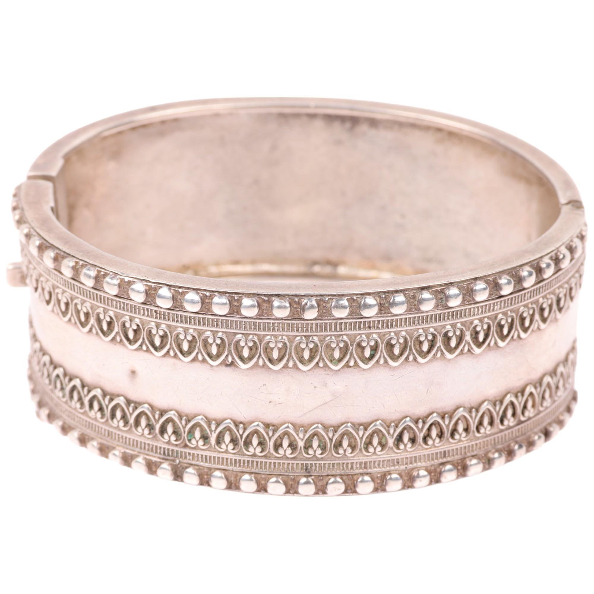 A Victorian sterling silver hinged bangle, with relief heart decoration, band width 24.8mm, internal