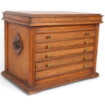 An Arts and Crafts oak collector's chest, having a rising lid above 5 fitted drawers and ring