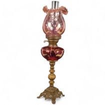 Antique cast and pierced brass oil lamp, with cranberry glass font and shade, with chimney, H67cm