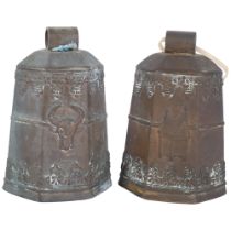 A pair of hexagonal embossed bronze cowbells, with cow's head and building decoration, and wooden