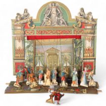 A wooden Victorian theatre scene, includes background scenery and associated theatre performers