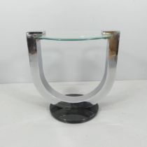 A contemporary circular glass top occasional table on polished metal supports in the manner of