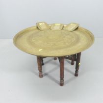 An eastern brass tray-top table with folding base, 68x42cm, and tree brass pin trays. (4).