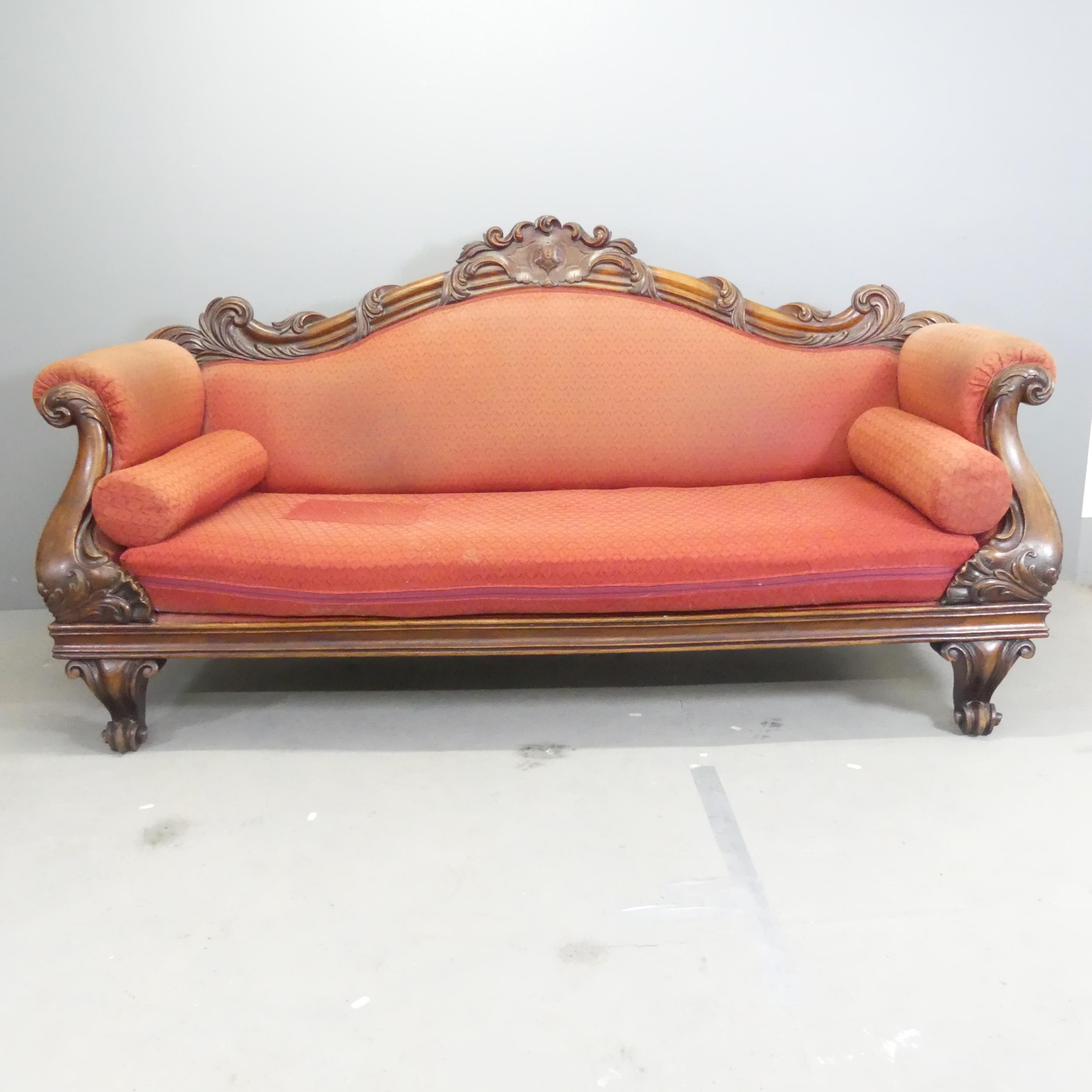 A Victorian mahogany and upholstered sofa, with carved acanthus leaf and lion paw decoration.