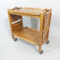 JOHN WATTS - A 1930s oak two-tier tray top tea trolley with folding cake stand ends. 66x69x38cm.