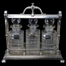 A Victorian electroplate 3-bottle tantalus, containing 3 moulded glass decanters, with silver wine