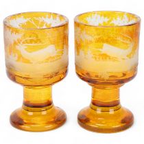 Pair of 19th century Bohemian amber overlay glass goblets, with engraved stags, on heavy bases,