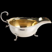 An Edwardian silver sauce boat, Wilson & Gill, London 1903, C-shaped handle with gilt interior,