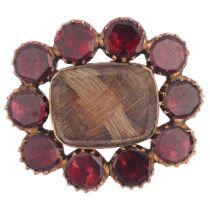 A Georgian flat-top garnet and hairwork mourning brooch, circa 1820, central woven hair panel