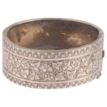 A Victorian sterling silver hinged bangle, engraved floral decoration, band width 24.5mm, internal