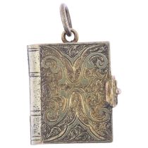 A Victorian novelty book photo locket pendant, the engraved covers opening to reveal arched interior