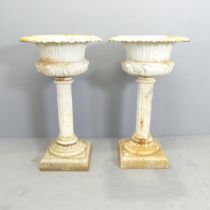A pair of antique painted cast iron Campana style urns, on fluted columns with pedestal base.