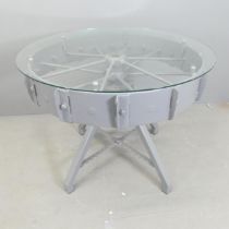 A contemporary circular glass topped table, on painted tractor wheel base. 95x76cm