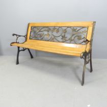 A modern pine slatted garden bench, with cast metal ends and inset gilded metal floral design