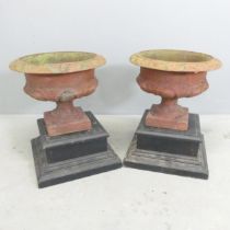 A pair of antique cast iron Campana style urns on painted wooden plinth stands. Dimensions (Urn