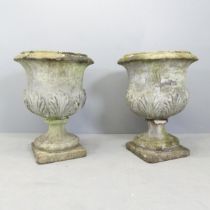 A pair of weathered concrete garden urns, with shell decoration. 54x71cm. One urn is in two