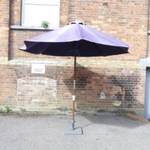 A garden parasol on cast metal base. Approximate height 250cm.