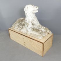 A weathered and painted cast stone garden statue, study of a hound, displayed on plywood plinth.