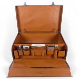 An early 20th century leather-covered gentleman's travelling vanity suitcase, the lid opening to