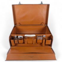 An early 20th century leather-covered gentleman's travelling vanity suitcase, the lid opening to