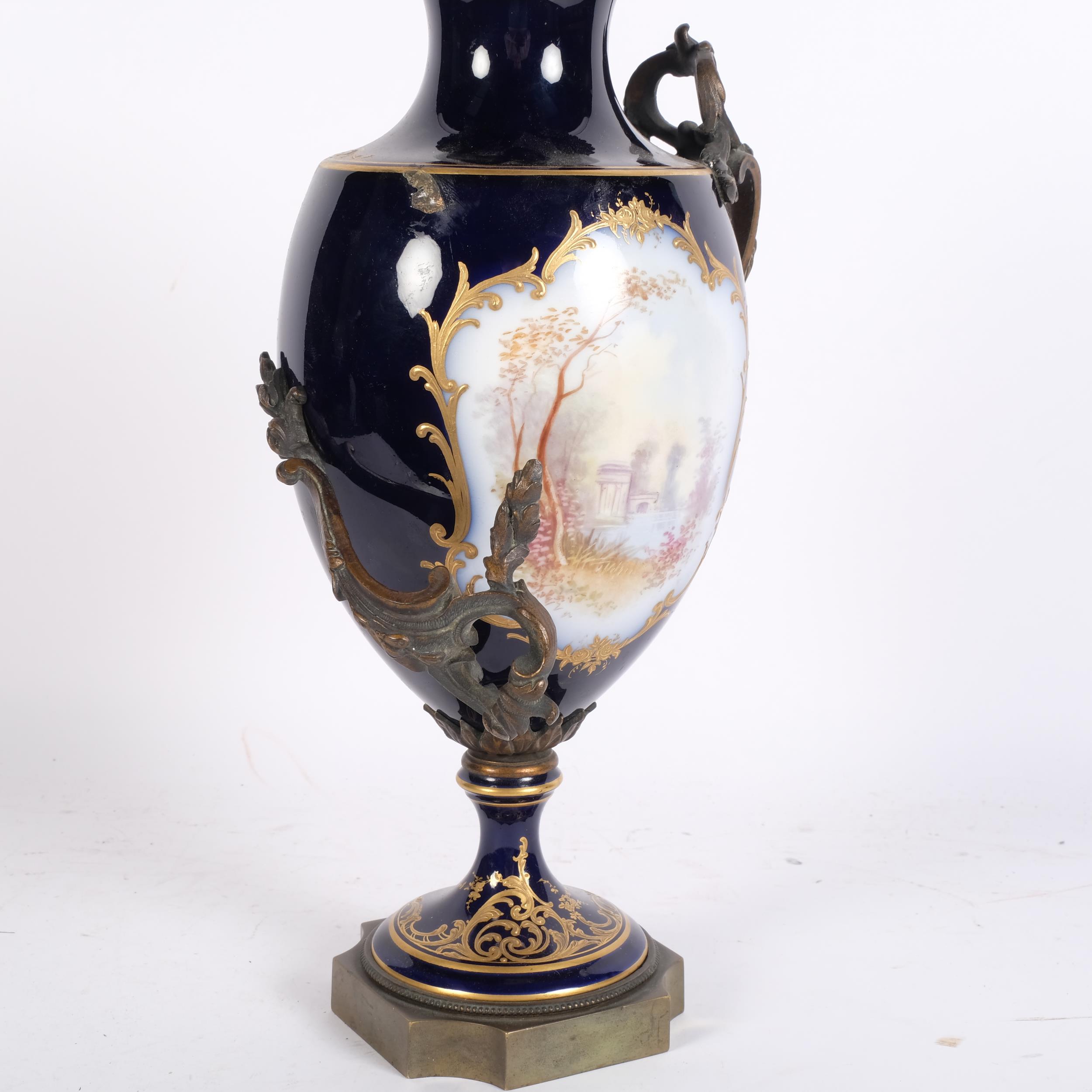 A French blue ground porcelain urn, with hand painted and gilded panels, and gilt-bronze handles and - Image 2 of 2