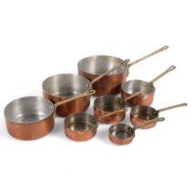 A graduated set of copper pans with brass handles Largest diameter 16cm, length 31cm. Smallest 6.5cm