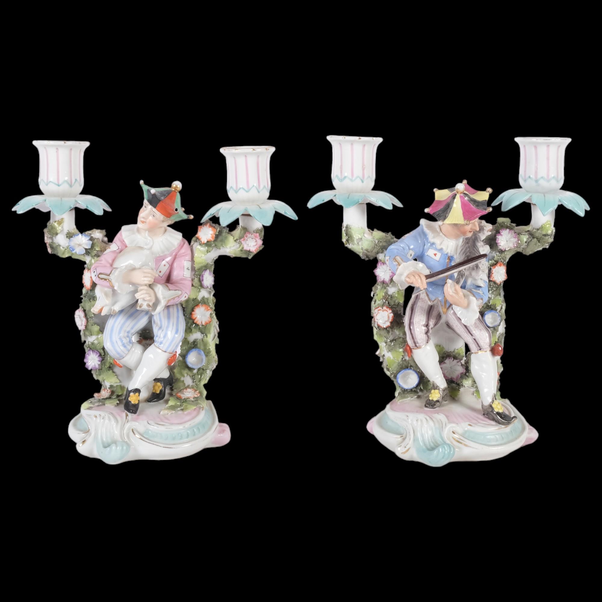 A pair of unusual German candelabra, with jester figures playing a cat and pig as musical