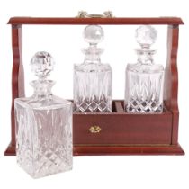 A mahogany 3-bottle tantalus, with crystal decanters, W43cm