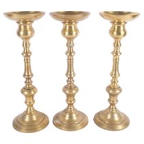 A set of 3 turned brass candle holders, H49.5cm