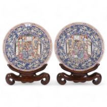 A pair of large Chinese famille rose chargers, enamelled figural decoration, hardwood stands,
