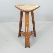 An Arts & Crafts oak triangular two-tier occasional table. Height 68cm.