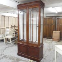 A modern mahogany two-section display cabinet, with two glazed doors, single adjustable shelves