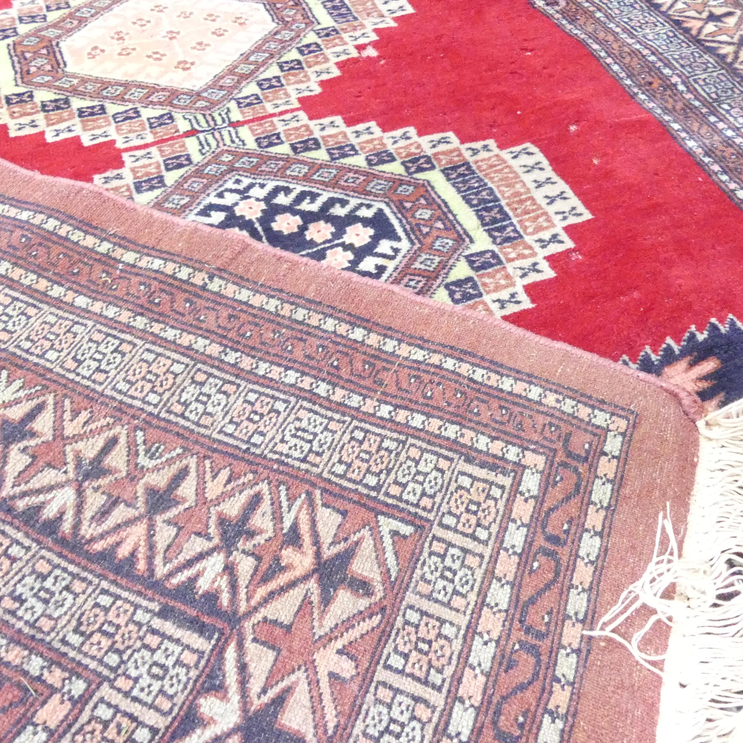 A handmade red ground Uzbek Bokhara rug. 205x130cm. - Image 2 of 2