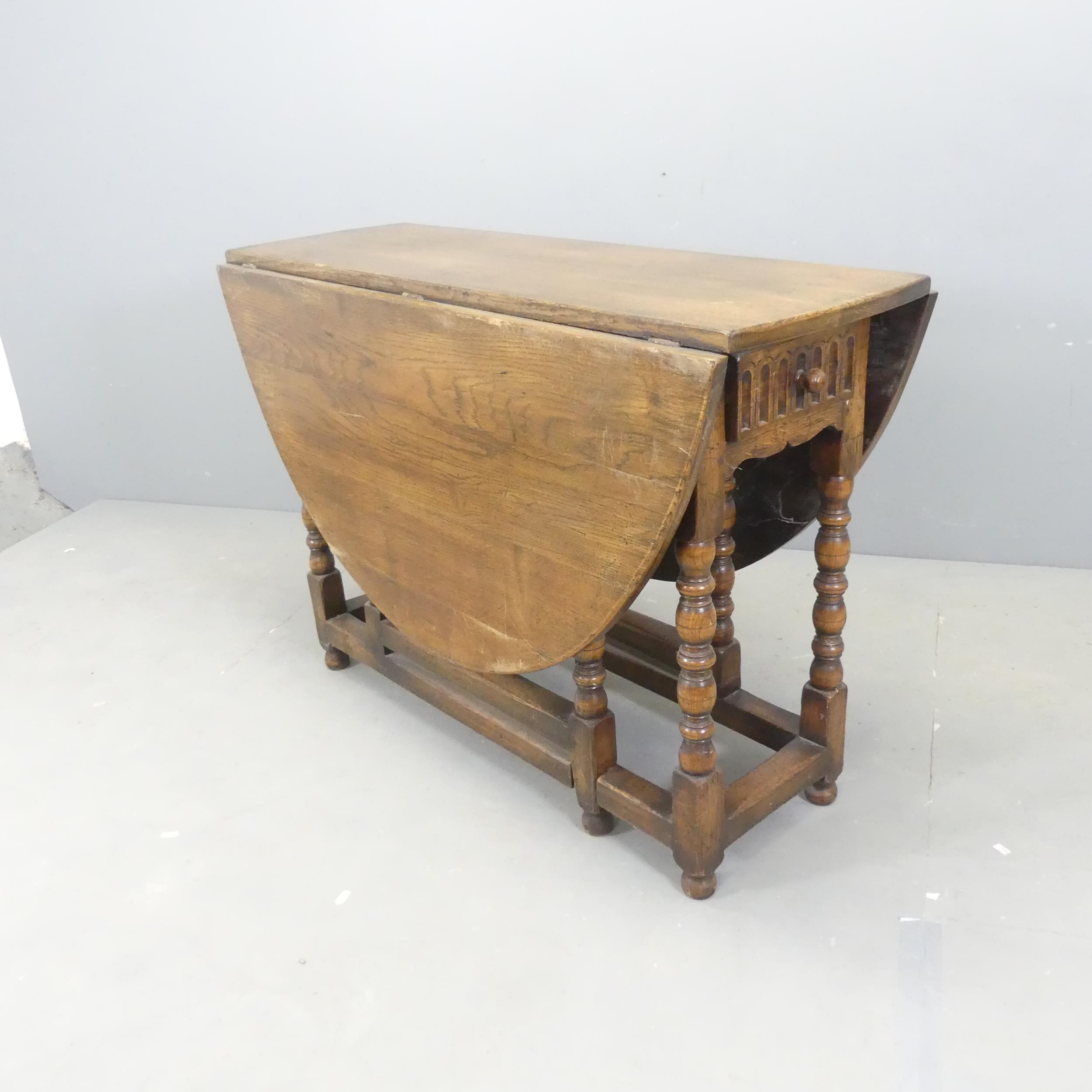 An early 20th century oak oval gate-leg dining table, with linenfold carved decoration, end frieze