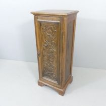 An oak Arts & Crafts style cabinet, with single door, two adjustable shelves, applied carved
