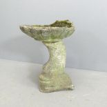 A two-section weathered concrete bird bath with shell design on oriental fish base. Height 50cm.