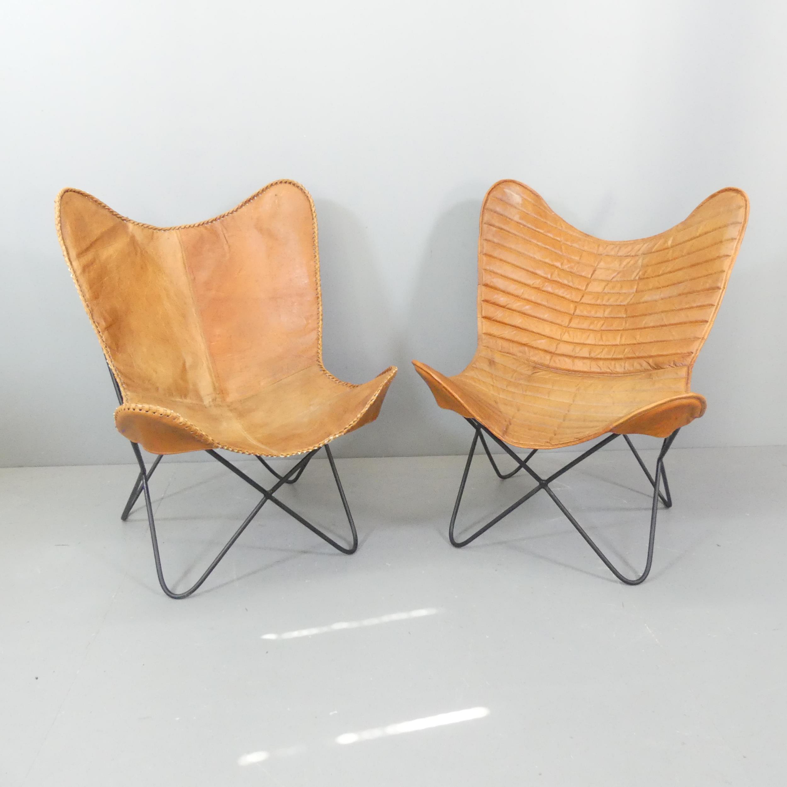 A pair of mid-century design butterfly chairs, with leather sling seats on tubular metal frames.