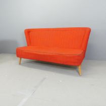 A mid-century cocktail sofa, upholstered in red boucle fabric on pine frame and raised on oak