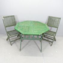 A painted teak octagonal folding garden table, 102x74cm, with two matching chairs.