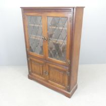 A reproduction oak bookcase, with two lattice glazed doors and cupboards under. 87x124x27cm.