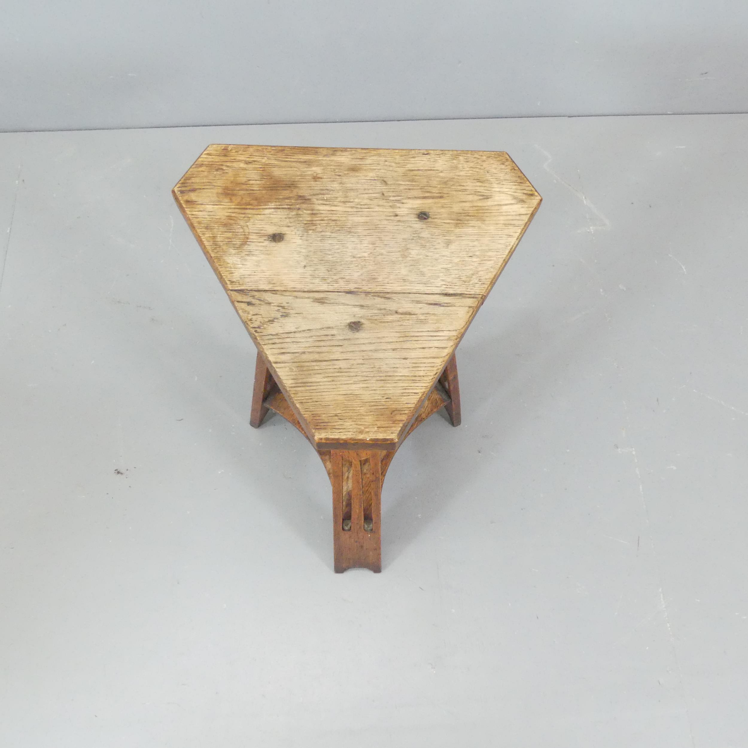 An Arts & Crafts oak triangular two-tier occasional table. Height 68cm. - Image 2 of 2