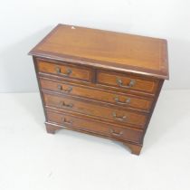 A reproduction oak mahogany and satinwood strung chest of two short and three long drawers, raised